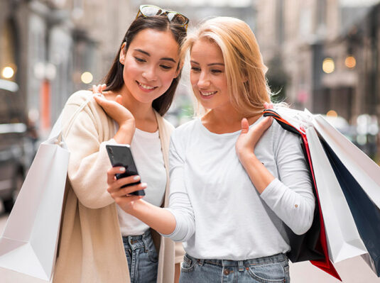 Giovani donne che fanno shopping cercano su smartphone